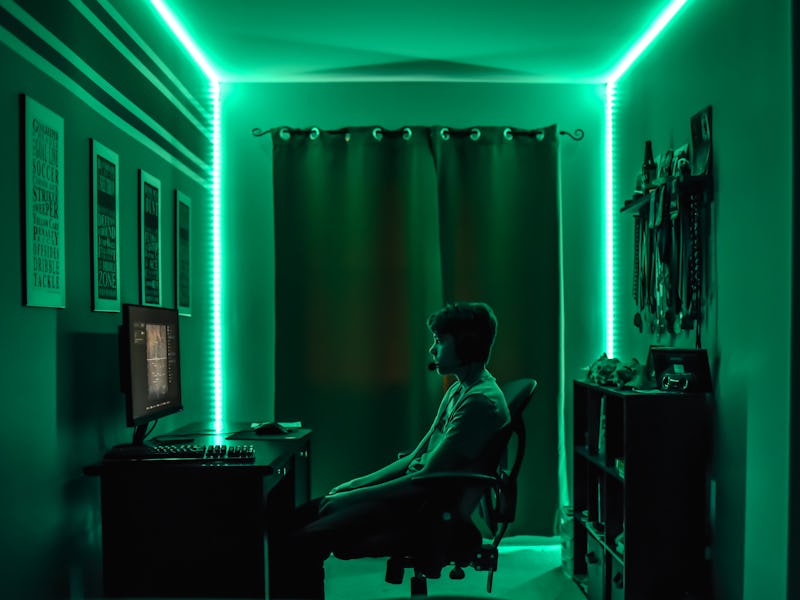 Man playing games on a PC in a darkly lit room.