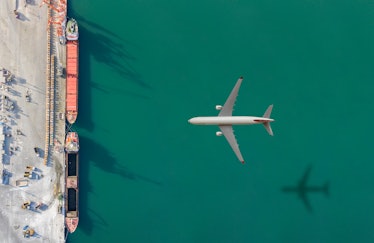 Airplane flying above commercial dock.