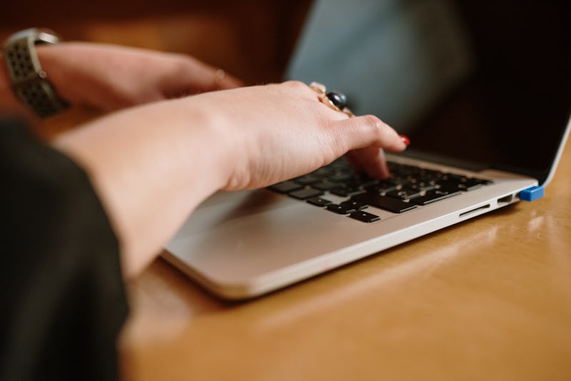 Detail of a woman typing on a laptop keyboard indoors