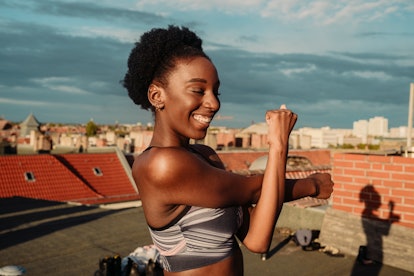 A young woman stretches before doing a sun salutation on the roof of her apartment building.