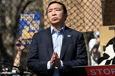 andrew yang in front of protest signs UBI