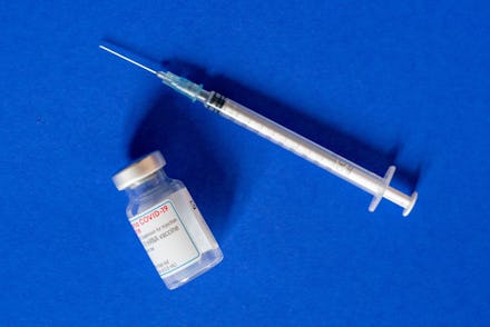 22 March 2021, Saxony, Leipzig: A vaccine ampoule from the company Moderna lies next to a vaccinatio...