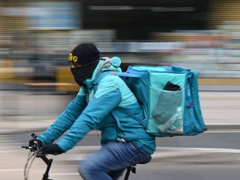 A Deliveroo rider cycles through central London on March 26, 2021. - The meal delivery platform Deli...