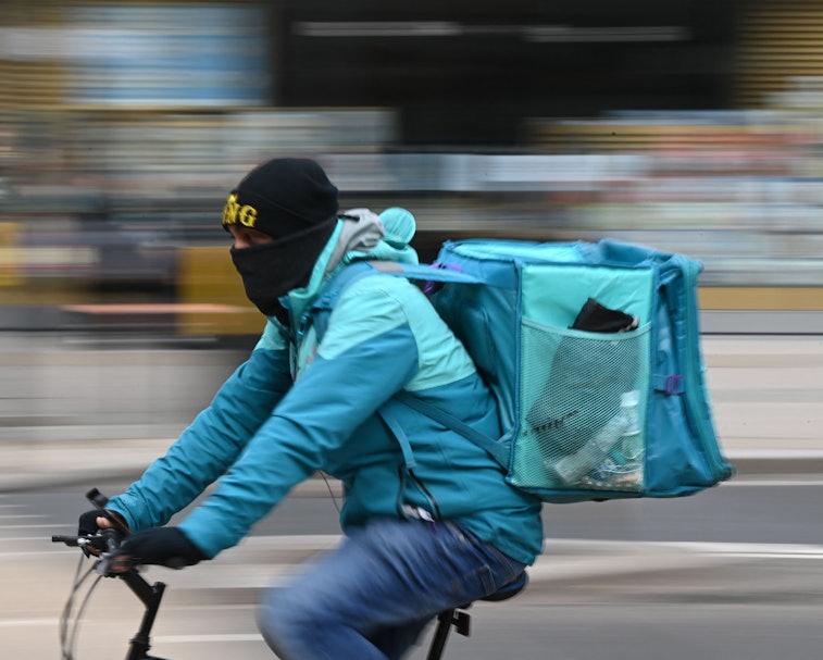 A Deliveroo rider cycles through central London on March 26, 2021. - The meal delivery platform Deli...
