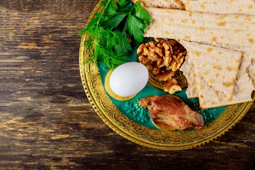 A seder plate sits on a wooden table. Hosting a seder over Zoom can be tricky, but you can still mak...