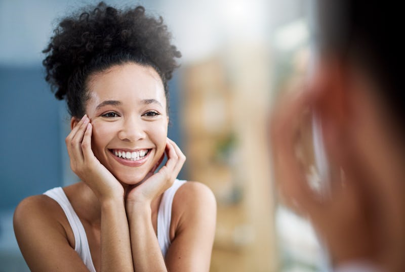 Cropped shot of an attractive young woman standing alone and using a mirror in the bathroom at home