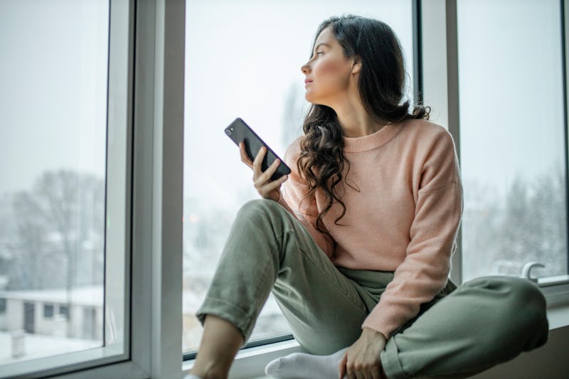 Depressed woman at home feeling sad. Woman looks sadly outside the window. Depressed lonely lady sta...