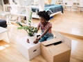 A young woman unpacks a funny planter on Etsy while sitting in her bright apartment.
