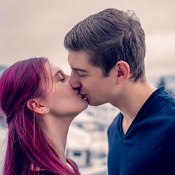 Young couple kisses on the balcony of their new home. In the background the snowy landscape.