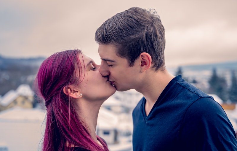 Young couple kisses on the balcony of their new home. In the background the snowy landscape.