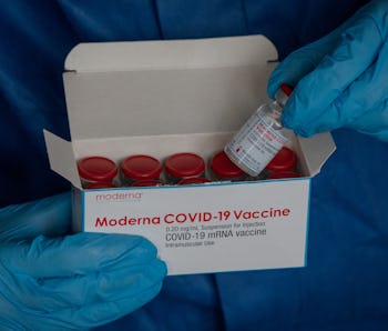 23 March 2021, Saxony, Leipzig: A hand with disposable gloves takes a vaccine ampoule of the company...