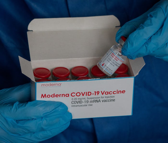 23 March 2021, Saxony, Leipzig: A hand with disposable gloves takes a vaccine ampoule of the company...