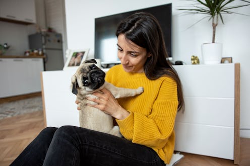 Beautiful young woman playing with her little dog pug