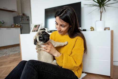 Beautiful young woman playing with her little dog pug