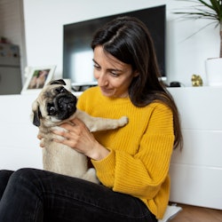 Beautiful young woman playing with her little dog pug
