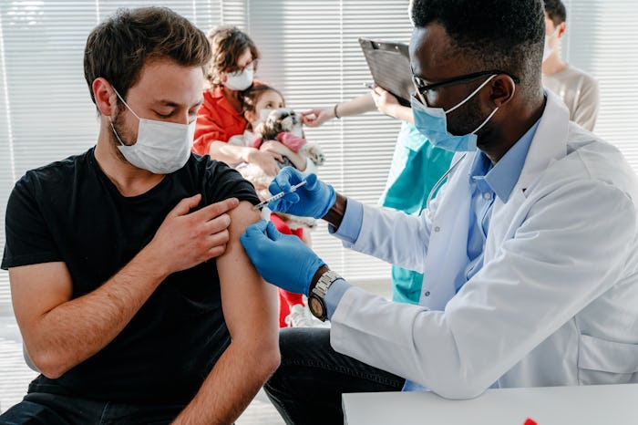 young man with face mask getting vaccinated, coronavirus, covid-19 and vaccination concept
