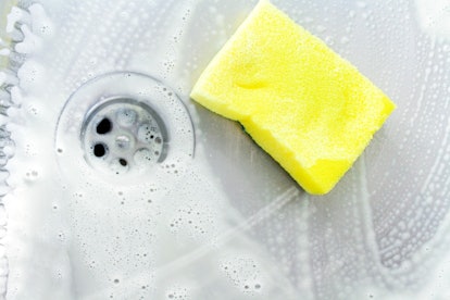 cleaning a sink with yellow sponge and cream cleanser
