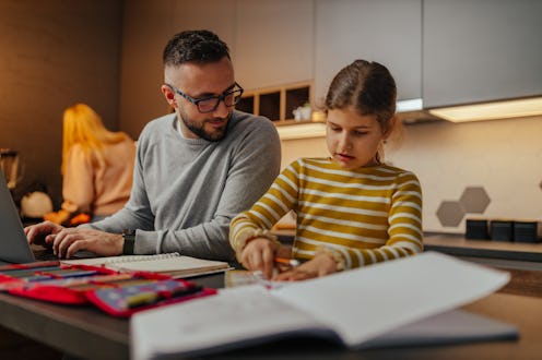 Father helping out his daughter with studying at home.