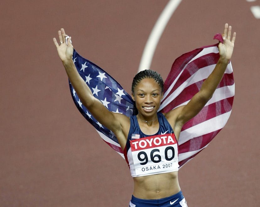 Allyson Felix holds an American flag behind her as she runs a "victory lap" around a track field.