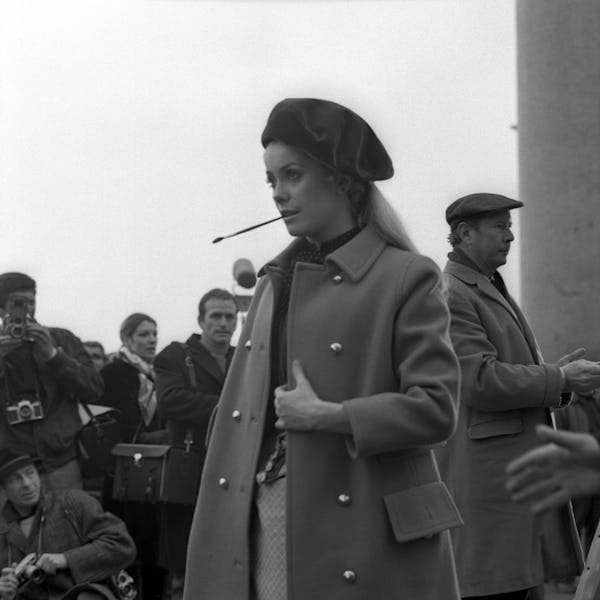 French actress Cathrine Deneuve on the set of the movie 'Mayerling', wearing a coat and and a beret,...
