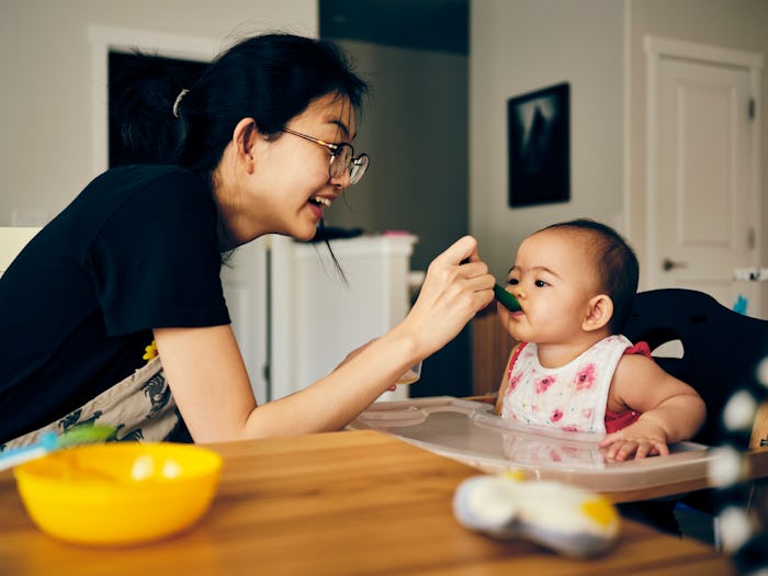 A Japanese mother feeds her 7 month old baby dinner in their home.