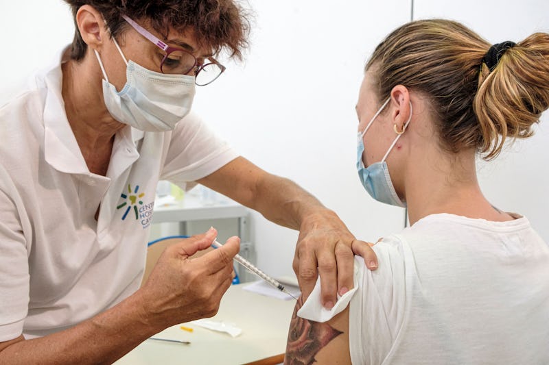 A woman receives a COVID vaccine. People who are vaccinated against COVID have to wait at least two ...