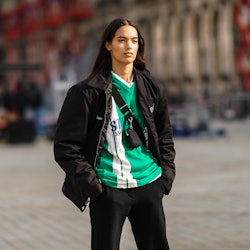 PARIS, FRANCE - MARCH 09: A model wears a a black jacket, a green and white stripe v-neck soccer t-s...