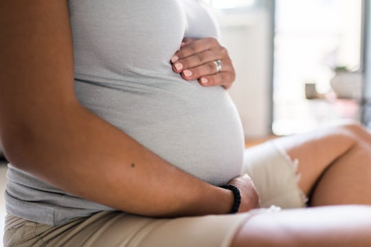 Pregnant woman embracing her pregnant belly.