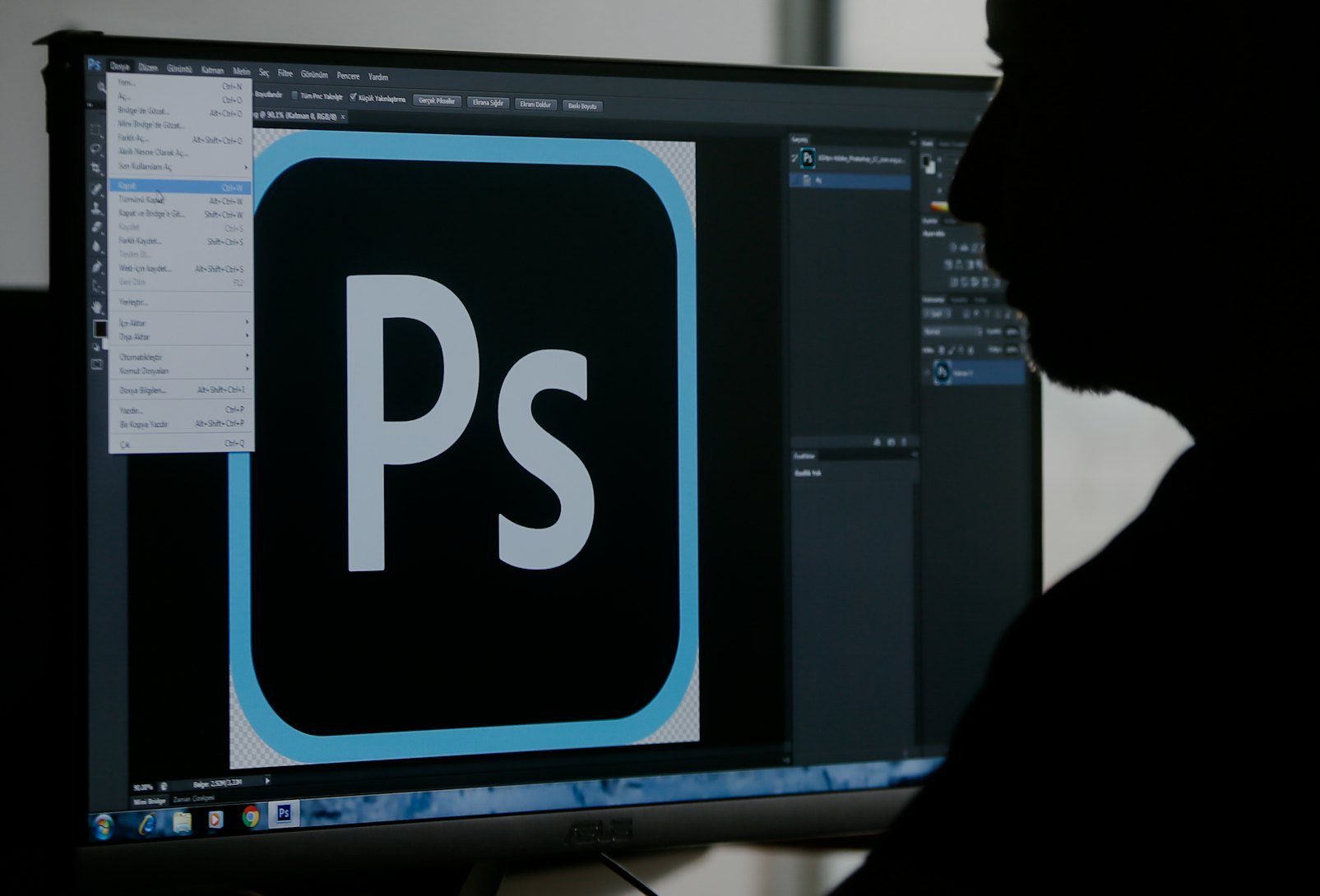 A person sitting at a computer using Photoshop.