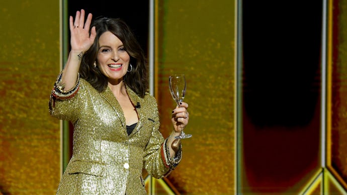 Tina Fey in a golden blazer waving at an award show