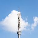 Cellular network tower in front of a blue sky.