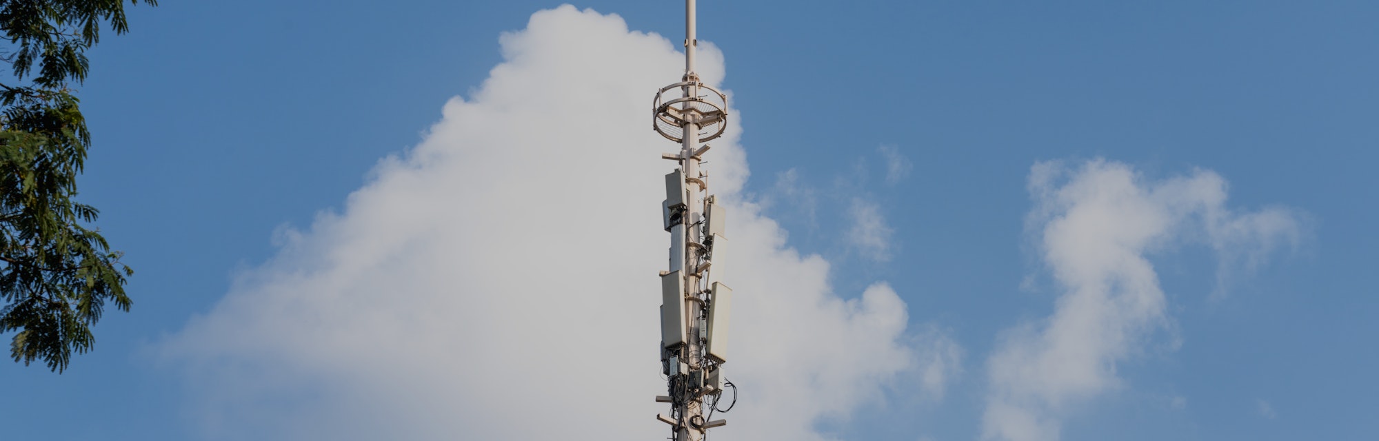 Cellular network tower in front of a blue sky.