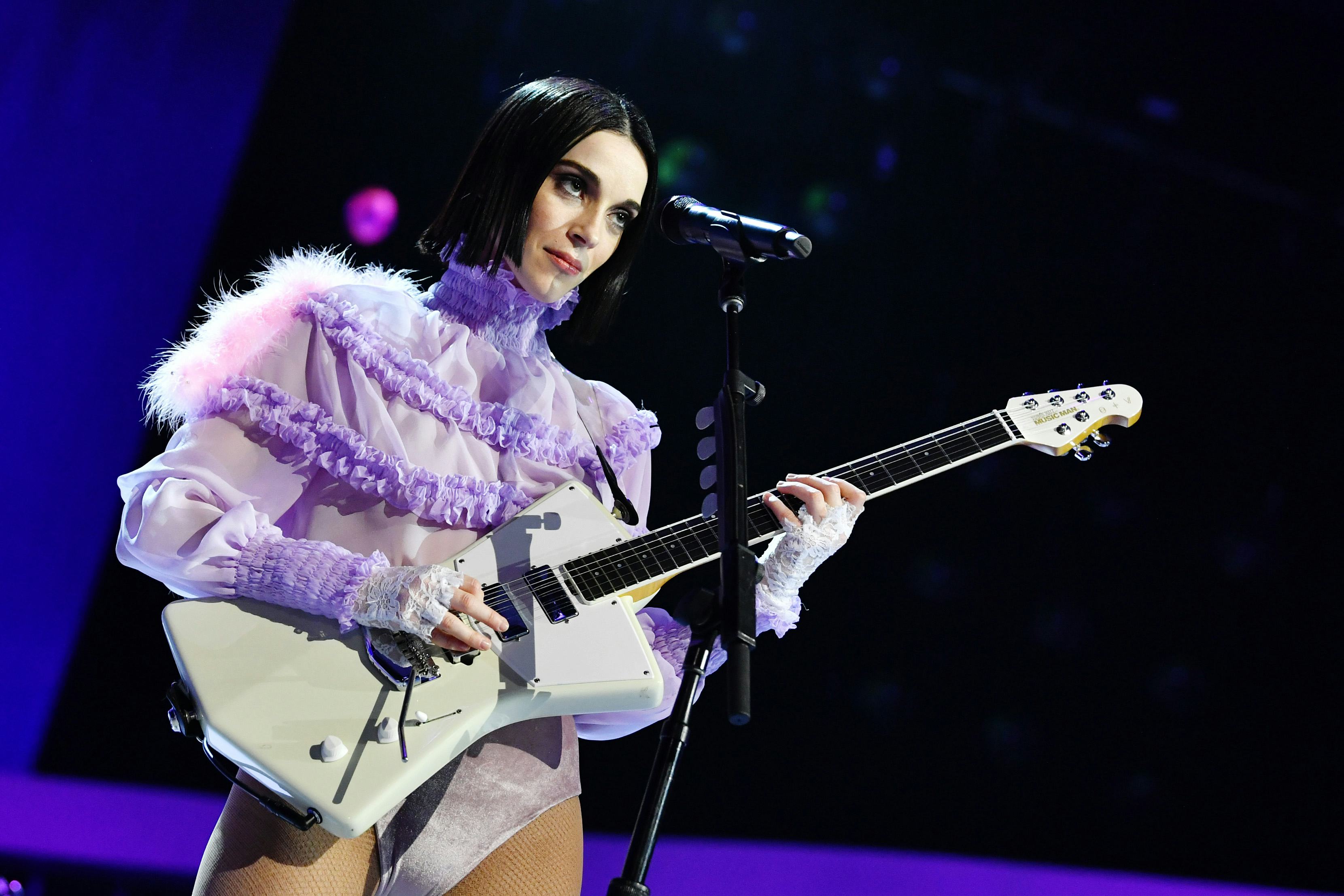 Annie Clark (St. Vincent) playing guitar in a purple ruffled shirt