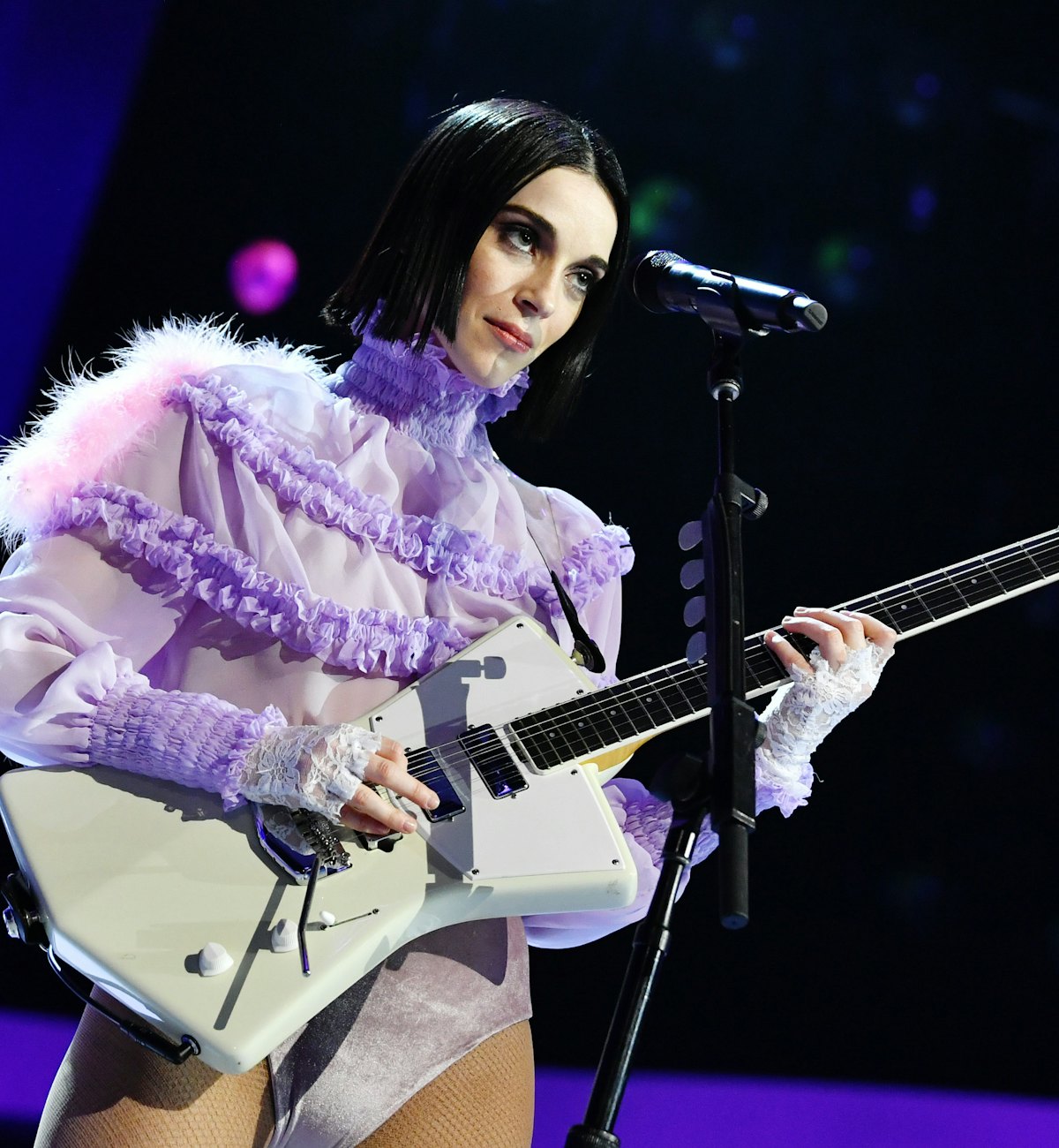 Annie Clark (St. Vincent) playing guitar in a purple ruffled shirt