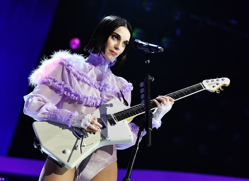 Annie Clark (St. Vincent) playing guitar in a purple ruffled shirt