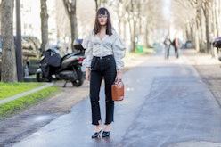 PARIS, FRANCE - MARCH 02: Evangeline Smyrotaki wearing a white top, black denim jeans, brown bag, ou...