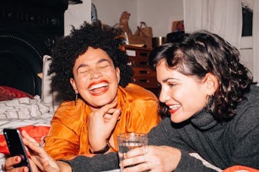 Two young women laugh while creating BFF Pinterest boards for each other.