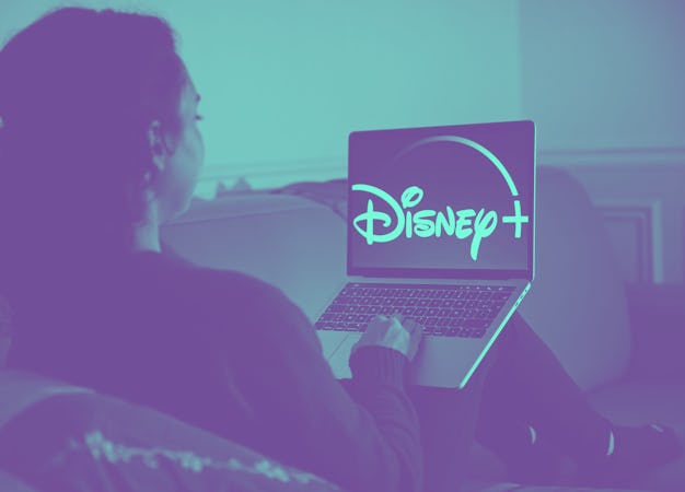 A woman is seen watching Disney+ on her laptop screen.