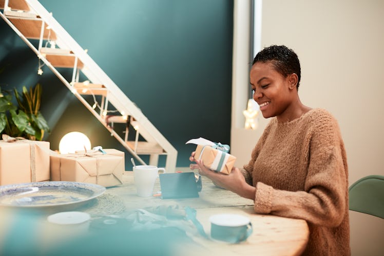A bride-to-be wraps up unique maid of honor gifts from Etsy while sitting in her living room.