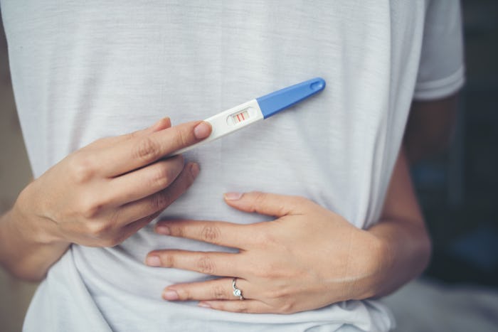 Happy couple smiling after find out positive pregnancy test in bedroom