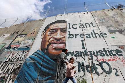People walk past a mural showing the face of George Floyd, an unarmed handcuffed black man who died ...