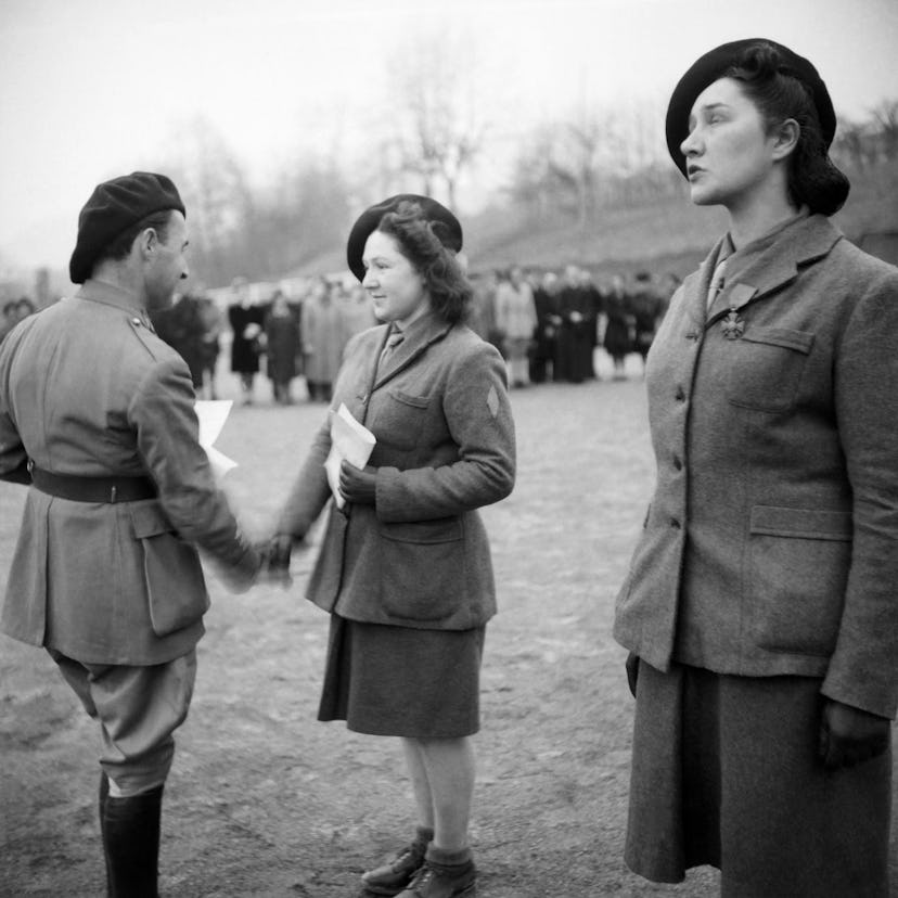 Xavier de Virieu (L) decorates with the Croix de Guerre young women during a military ceremony at th...