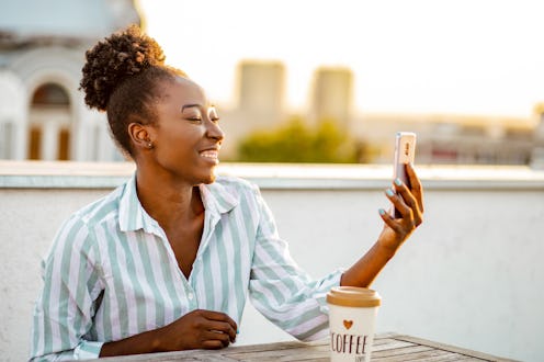 Young African American woman is on the balcony at sunset, she is talking to someone over video call