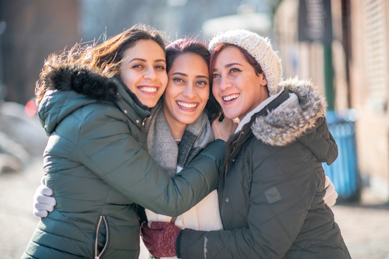 Three beautiful sisters of Middle Eastern ethnicity are standing outdoors on a winter day. They are ...