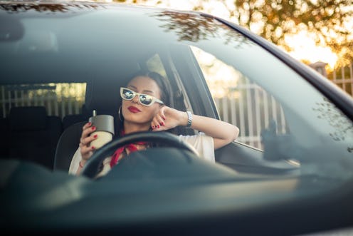 Businesswoman Driving. A photo of a young business woman in a car drinking coffee.