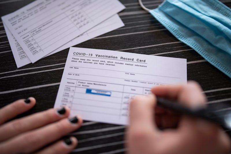 Unrecognizable woman filling COVID-19 vaccination record card.