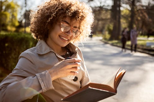 Young woman relaxing with a book and a cup of coffee outdoors