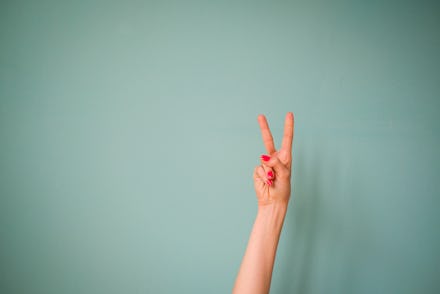 Hand peace sign in front of wall.