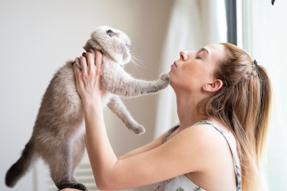 Young woman want kiss the cat. But cat dosn't want.