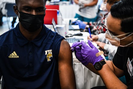 Pharmacy student Jason Rodriguez (R) administers a Covid-19 vaccine to Larry Grier at the Christine ...